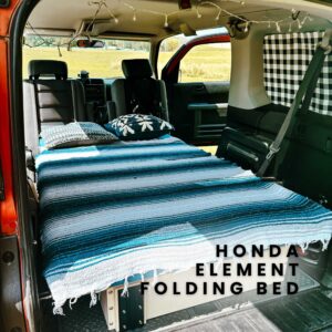 A Honda Element with a folding bed in the back. The bed is made up with a blue and white striped blanket and pillows. The text "HONDA ELEMENT FOLDING BED" is visible in the image.